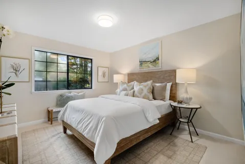 a bedroom with a bed mirror and window