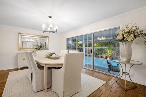 a dining room with wooden floor a chandelier a wooden table and chairs