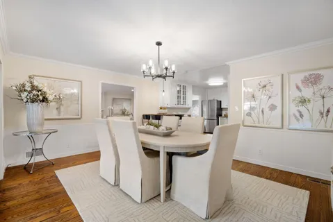 a kitchen with stainless steel appliances granite countertop a stove a sink dishwasher and white cabinets with wooden floor