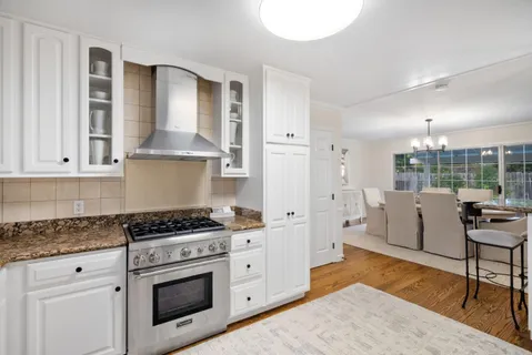 a kitchen with granite countertop stainless steel appliances a sink cabinets and a window