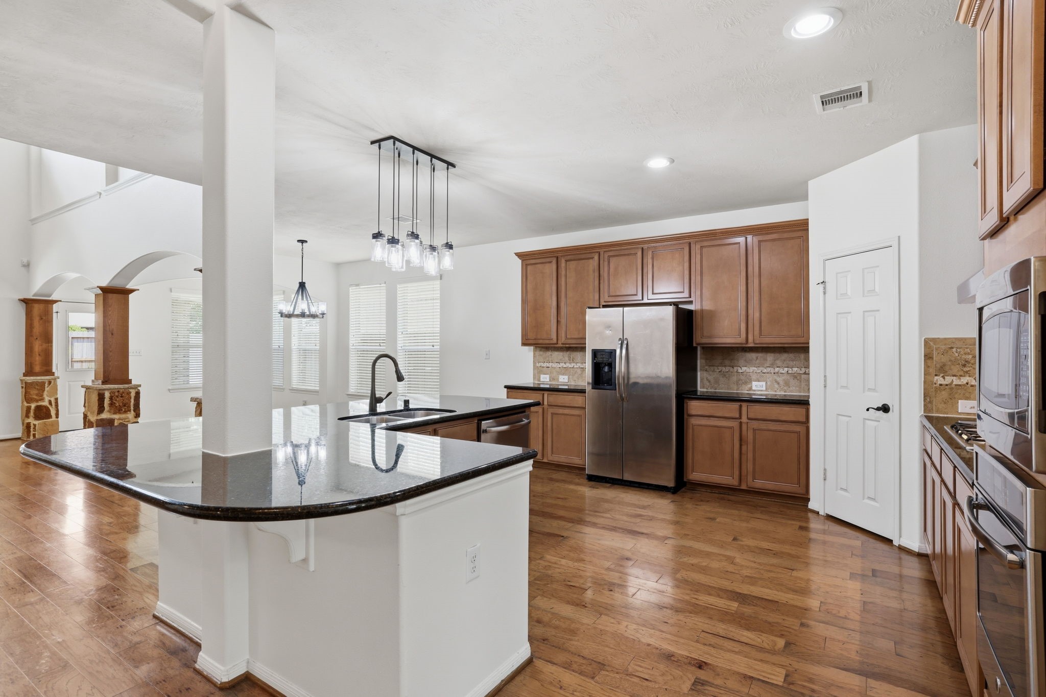 8169 Tranquil Lake Way Conroe, TX 77385 - Photo 9 of 26 a kitchen with stainless steel appliances granite countertop a refrigerator a sink a stove and a wooden floors