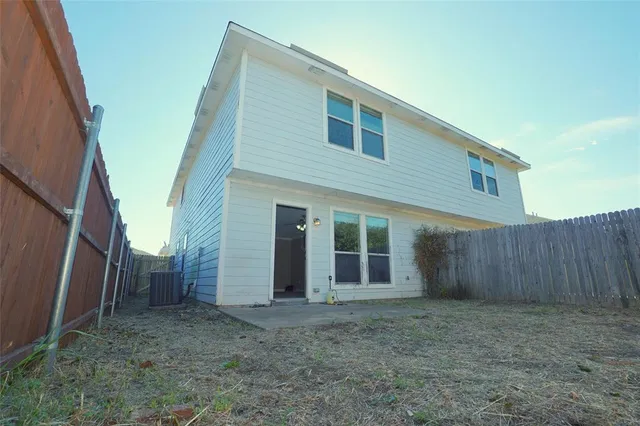 a view of a house with backyard and wooden fence