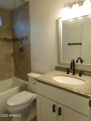 a bathroom with a granite countertop toilet sink and mirror