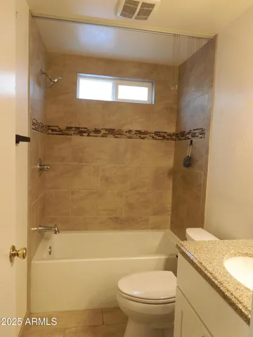 a bathroom with a granite countertop bathtub shower sink vanity and toilet