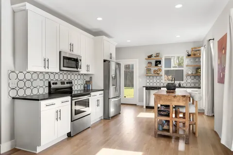 a kitchen with stainless steel appliances a microwave a stove a table and chairs