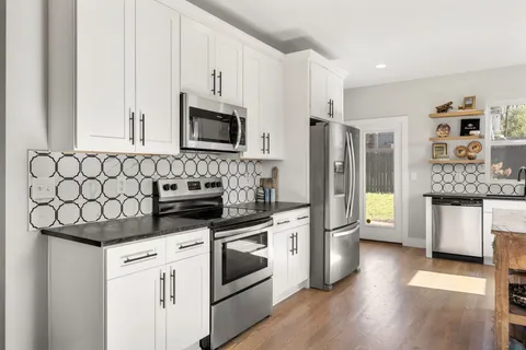 a kitchen with stainless steel appliances white cabinets and wooden floor