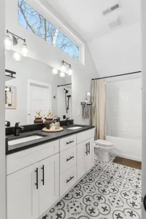 a bathroom with a double vanity sink a toilet and a shower