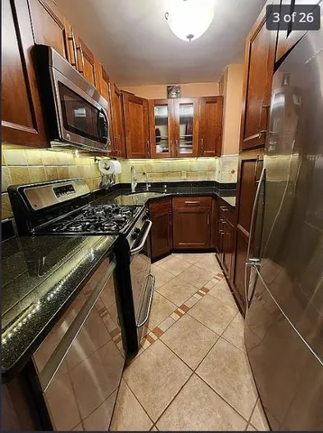 a kitchen with granite countertop stainless steel appliances a sink stove top oven and granite counter top