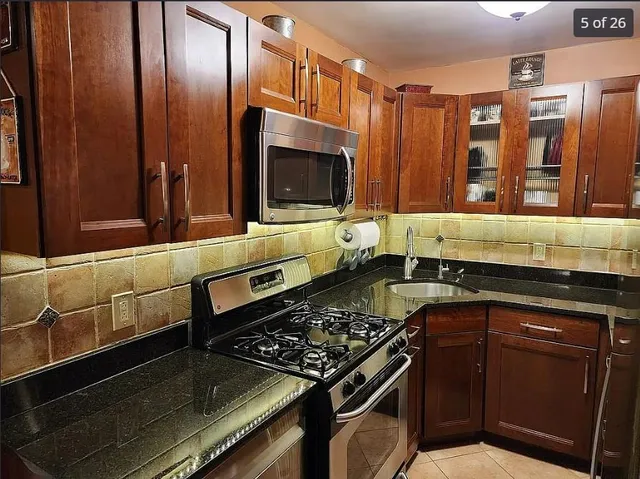 a kitchen with kitchen island granite countertop a stove and a sink