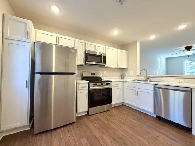a kitchen with a refrigerator stove and wooden floor