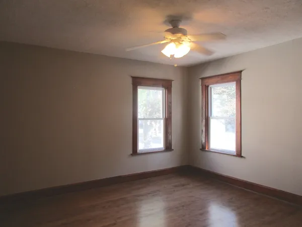 a view of an empty room with a window and wooden floor