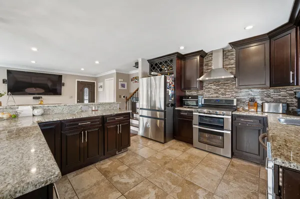 a large kitchen with stainless steel appliances kitchen island granite countertop a stove top oven a sink dishwasher and a refrigerator