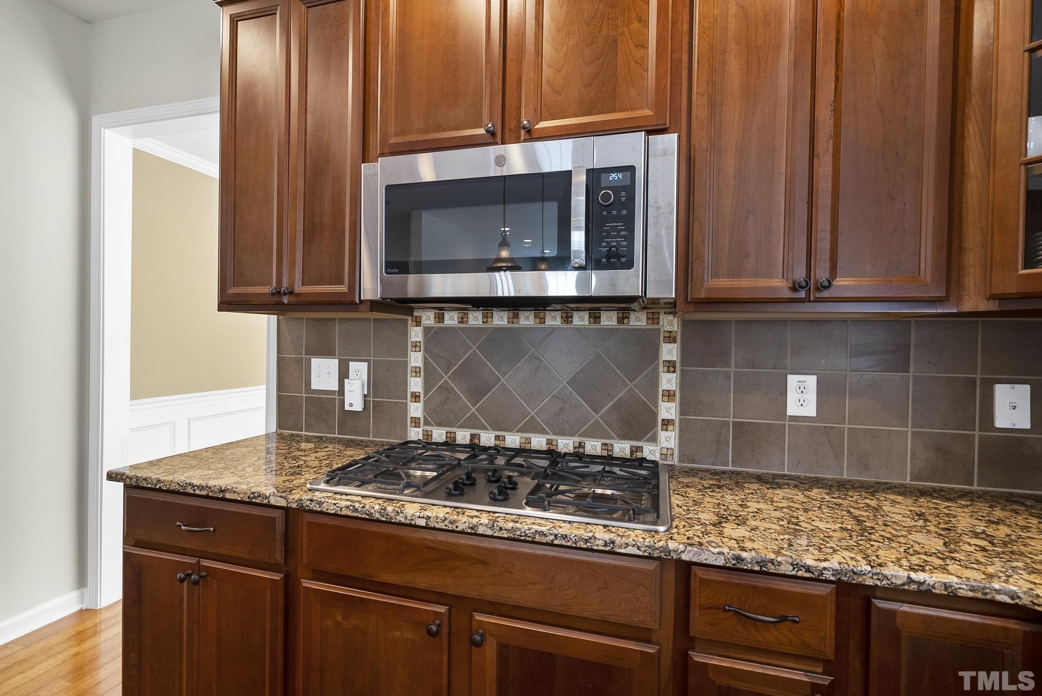 213 Forbes Road Wake Forest, NC 27587 - Photo 14 of 41 a kitchen with granite countertop wooden cabinets and a stove top oven