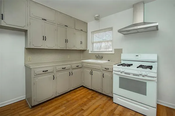 a kitchen with cabinets appliances and wooden floor