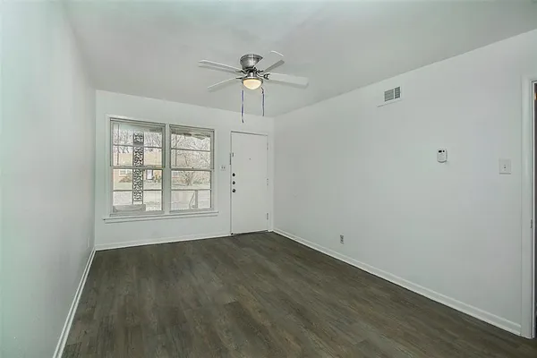 an empty room with wooden floor chandelier and windows