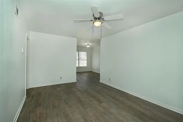 an empty room with wooden floor and fan