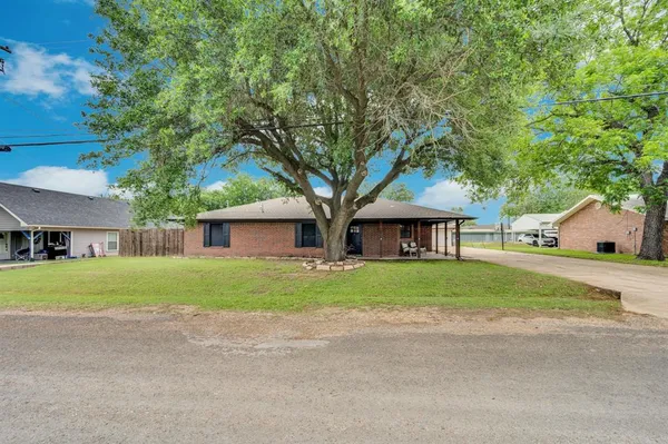 a view of a house with a yard and large trees