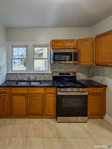 a kitchen with stainless steel appliances granite countertop a stove a sink and a microwave