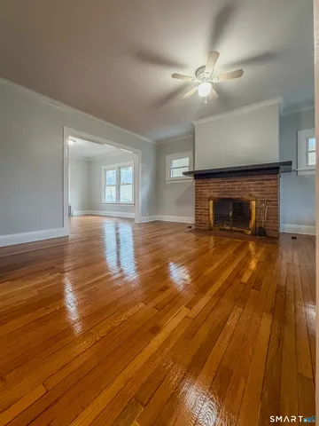 an empty room with wooden floor fireplace and chandelier