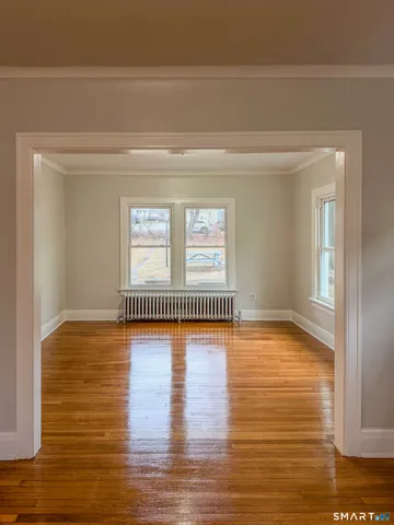 a view of empty room with window and wooden floor