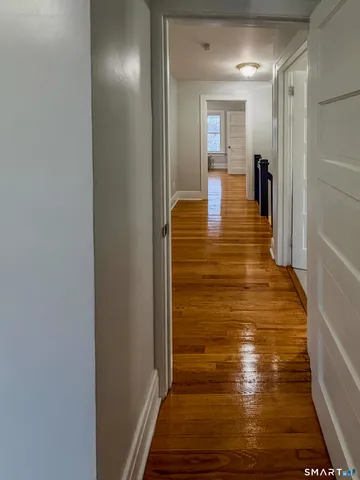 a view of a hallway with wooden floor and staircase