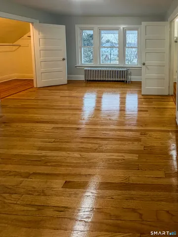 a view of empty room with window and wooden floor