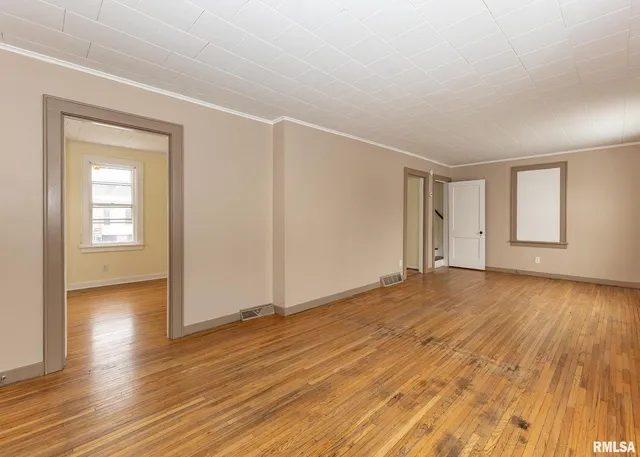a view of empty room with wooden floor and fan