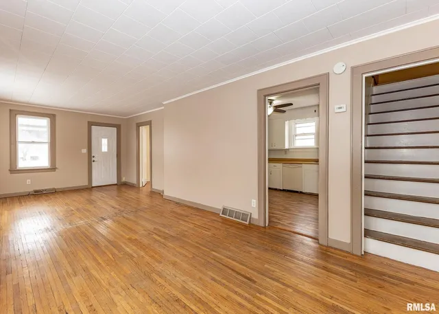 an empty room with wooden floor closet and windows
