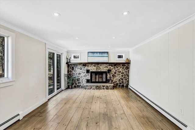 a view of an empty room with wooden floor fireplace and a window