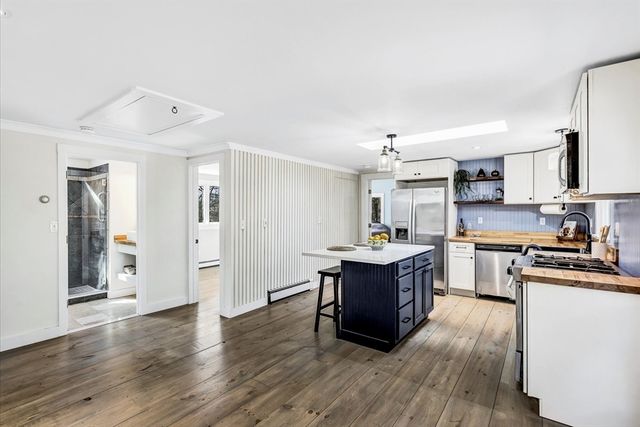 a kitchen with stainless steel appliances granite countertop a stove a sink dishwasher and a refrigerator with wooden floor