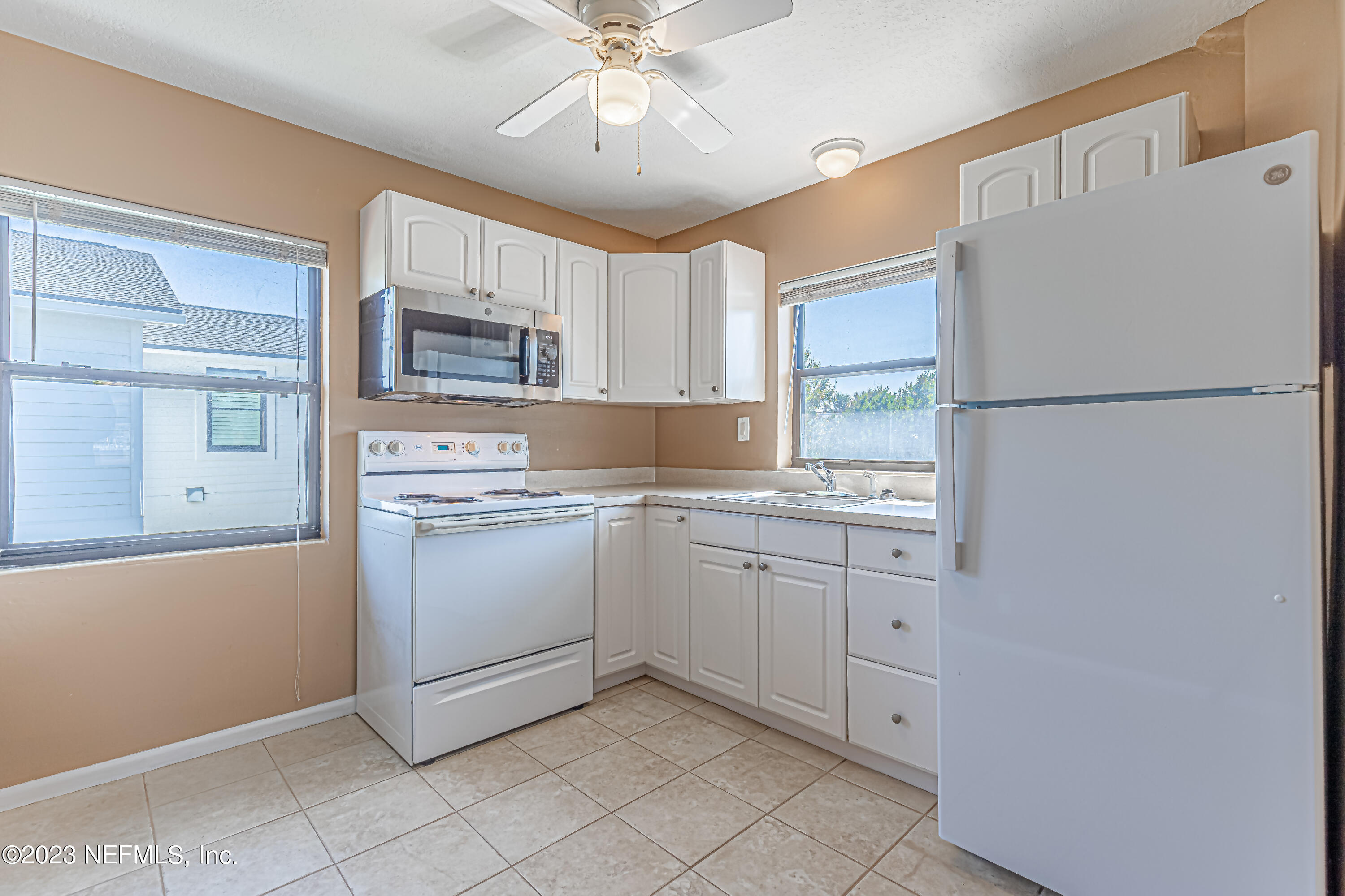 1907 First Street Neptune Beach, FL 32266 - Photo 12 of 29 a kitchen with white cabinets and white appliances