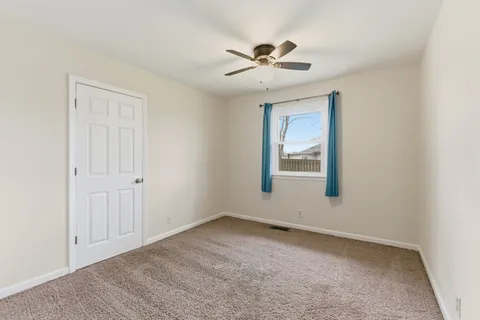 an empty room with ceiling fan and window