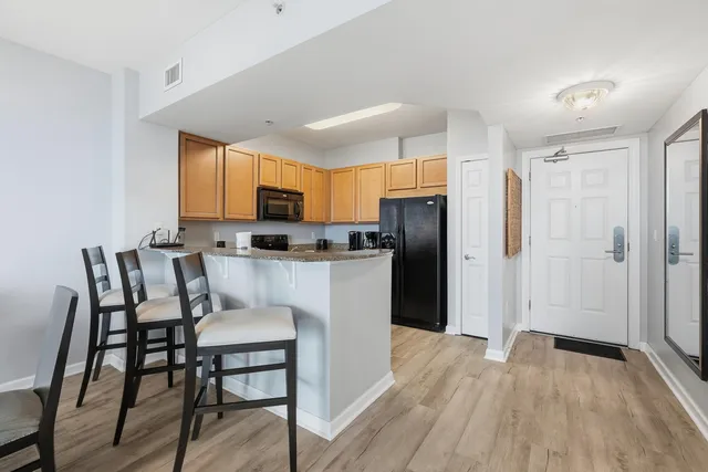 a kitchen with stainless steel appliances a refrigerator a stove top oven a sink dishwasher a dining table and chairs with wooden floor