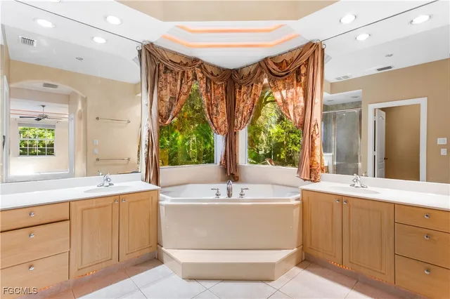 a bathroom with a sink a large mirror and a bathtub next to a window