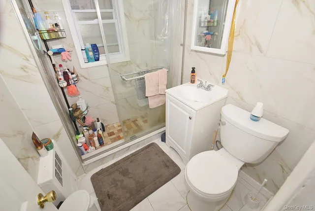 a white toilet sitting next to a bathroom sink and wooden floor