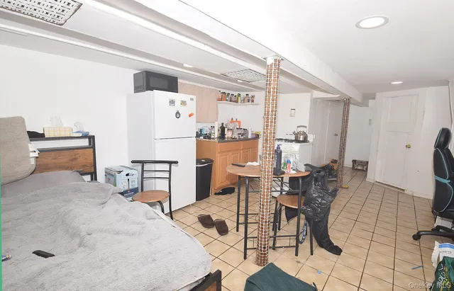 a living room with furniture and a refrigerator