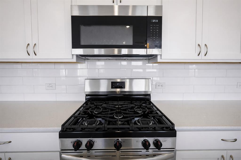 3017 Dutch Road Providence Village, TX 76227 - Photo 9 of 32 Kitchen with stainless steel appliances, light stone counters, white cabinets, and decorative backsplash