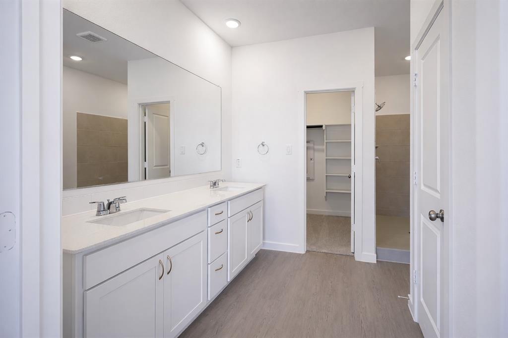 3017 Dutch Road Providence Village, TX 76227 - Photo 10 of 32 Bathroom featuring double vanity, dark wood finished floors, a tile shower, recessed lighting, and a walk in closet