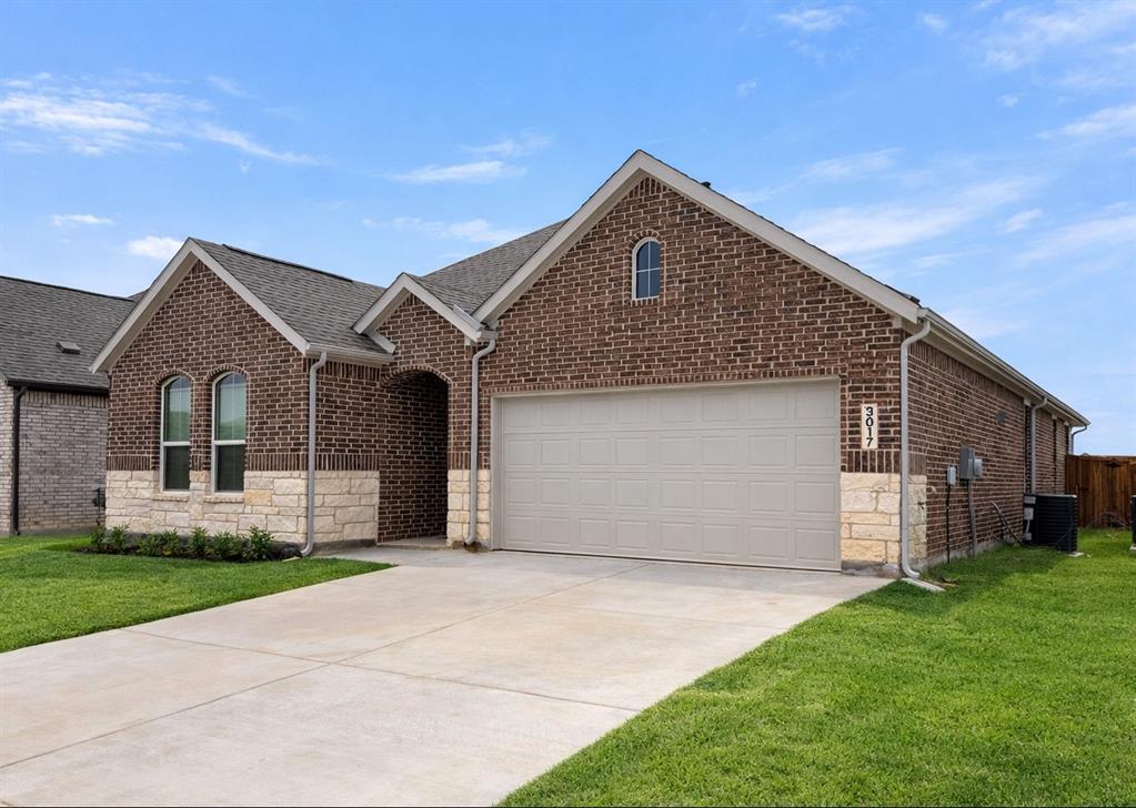 3017 Dutch Road Providence Village, TX 76227 - Photo 15 of 32 Ranch-style house featuring a front lawn, concrete driveway, stone siding, brick siding, and an attached garage