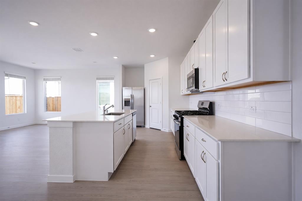 3017 Dutch Road Providence Village, TX 76227 - Photo 17 of 32 Kitchen featuring stainless steel appliances, white cabinets, an island with sink, light wood-style flooring, and recessed lighting