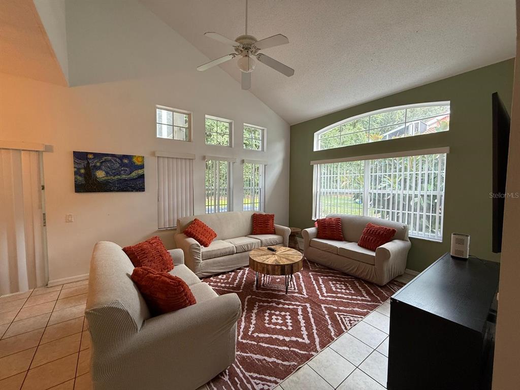 1013 Park Ridge Circle Kissimmee, FL 34746 - Photo 4 of 74 a living room with furniture a ceiling fan and a flat screen tv
