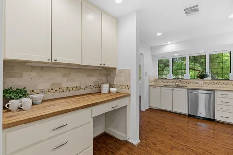 a kitchen with white cabinets stainless steel appliances and wooden floor