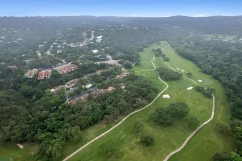 a view of a lush green forest with mountains in the background