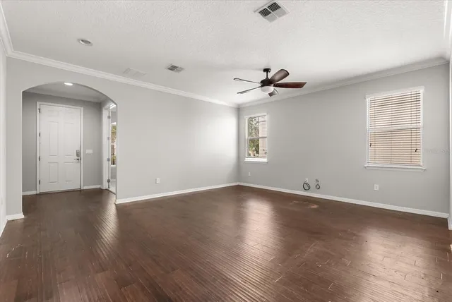 an empty room with wooden floor and windows