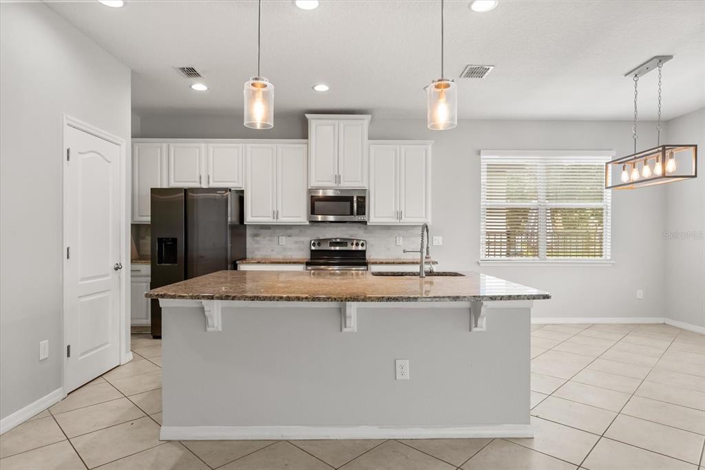 4345 Saltmarsh Sparrow Drive Windermere, FL 34786 - Photo 10 of 46 a kitchen with kitchen island a refrigerator a stove a sink and a microwave