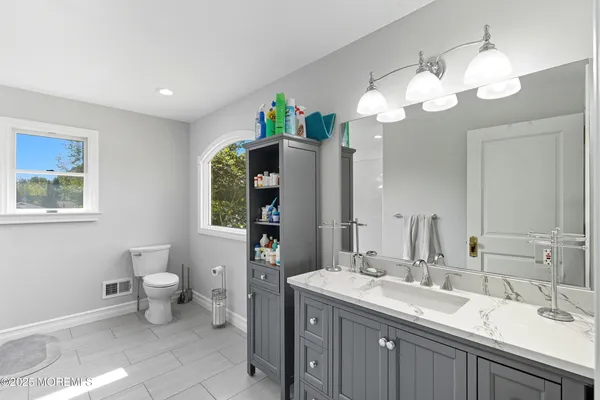 a bathroom with a granite countertop sink a toilet and a mirror