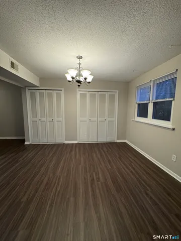 a view of an empty room with wooden floor and chandelier