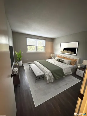 a bedroom with a bed a couch and potted plant on the dresser