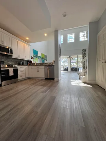 a large kitchen with stainless steel appliances wooden floors and view living room