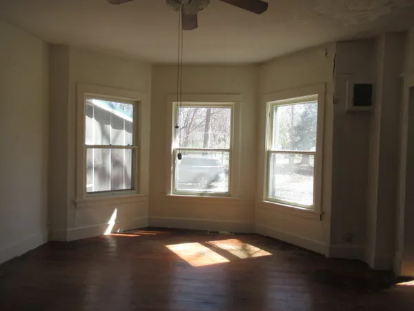 a view of an empty room with wooden floor and a window